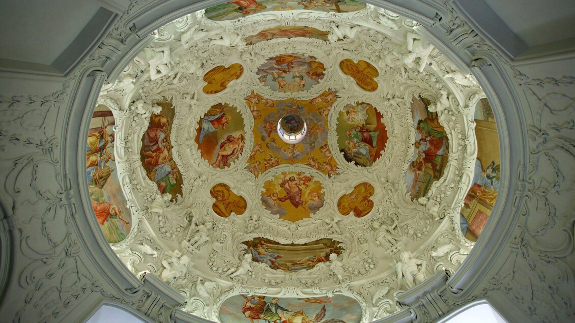 Eine kunstvoll gestaltete Decke mit bunten Fresken und detailreichen Verzierungen. Das Licht fällt durch eine zentrale Öffnung in der Mitte. | © Graz Tourismus - Harry Schiffer