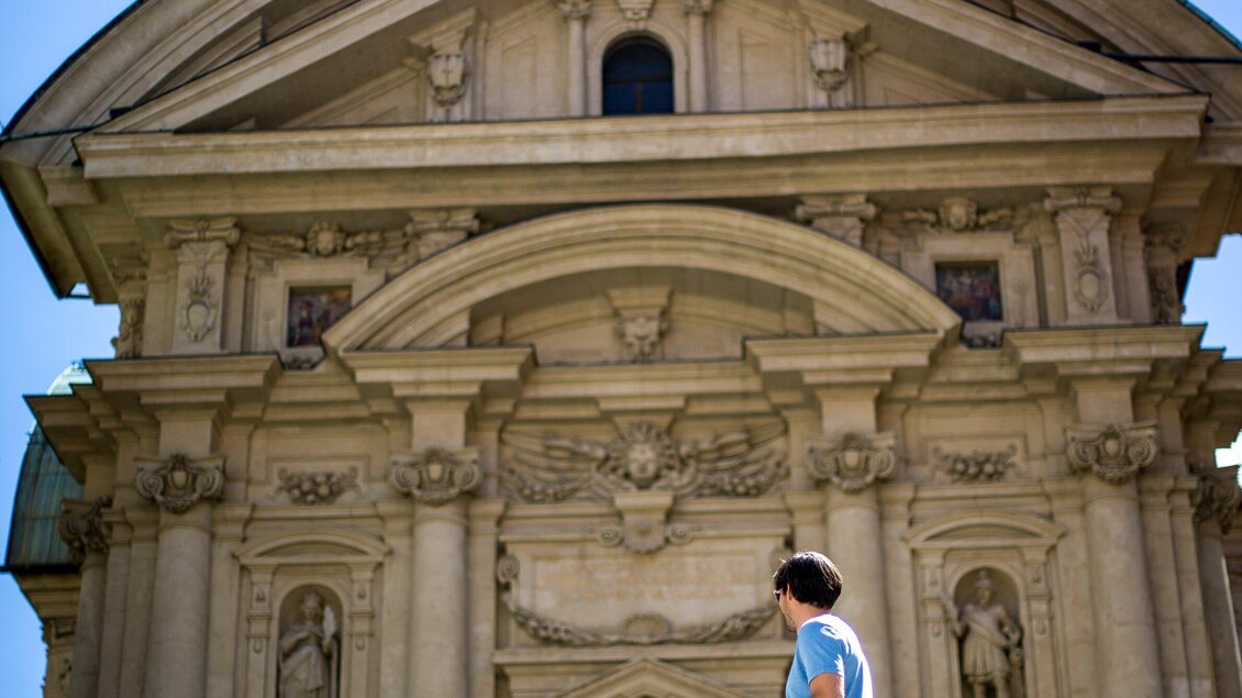 Eine eindrucksvolle historische Fassade mit kunstvollen Details. Eine Person steht davor und betrachtet die Architektur. | © Graz Tourismus - Tom Lamm