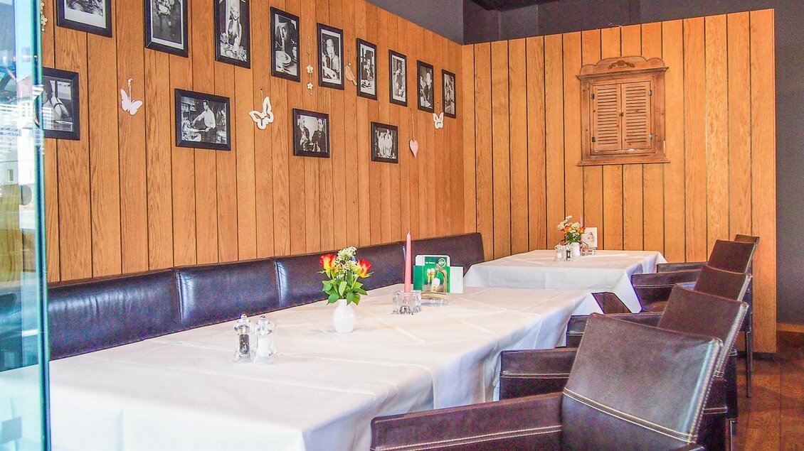 Ein gemütliches Restaurant mit Holzverkleidung und Bildern an der Wand. Der Tisch ist festlich gedeckt und mit Blumen dekoriert. | © Mediterran - Rathaus Restaurant
