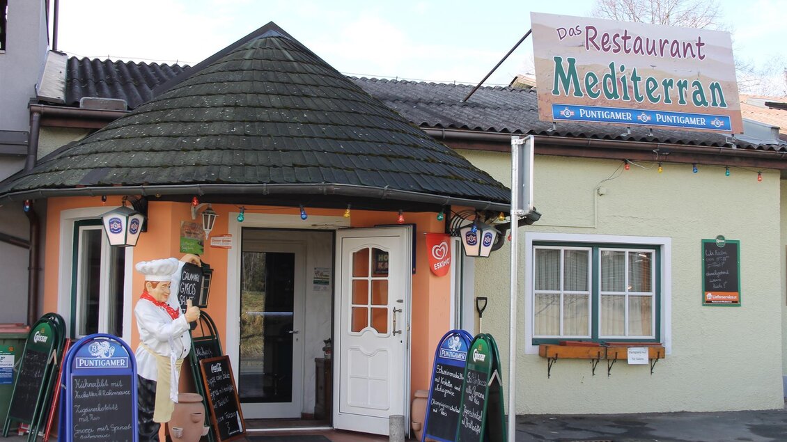 Ein gemütliches Restaurant mit dem Namen "Mediterran". Der Eingangsbereich ist einladend und hat eine dekorative Figur eines Kochs. | © Schilcherland Steiermark