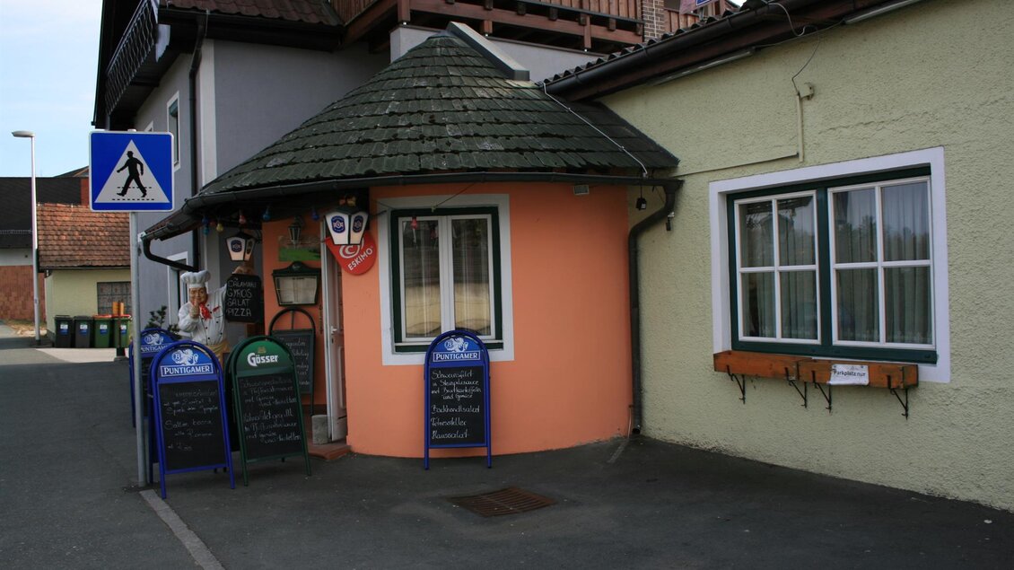 Ein kleines, rundes Gebäude mit einem schrägen Dach in sanften Farben. Vor dem Haus stehen Tafeln und ein Zebrastreifen ist sichtbar. | © Schilcherland Steiermark