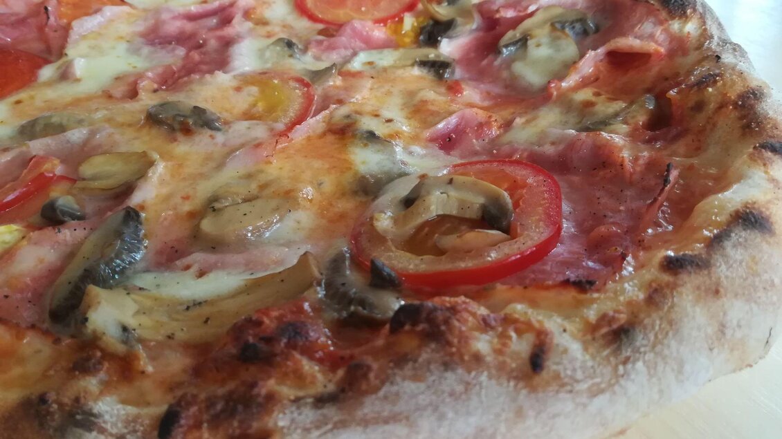 Eine leckere Pizza mit Schinken, Paprika und Pilzen. Der Rand ist knusprig und goldbraun. | © TV Südsteiermark - Irene Löschnig
