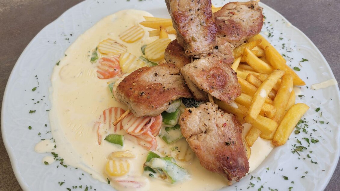 Ein Teller mit gebratenem Hühnchen, serviert mit Pommes Frites und einer cremigen Sauce. Dazu gibt es bunten Gemüse. | © TV Südsteiermark - Irene Löschnig