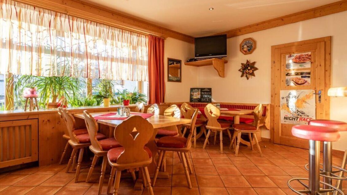 Ein gemütliches Restaurant mit Holzmöbeln und großen Fenstern. Pflanzen und eine einladende Atmosphäre sorgen für ein angenehmes Ambiente. | © Michis Bierstubn