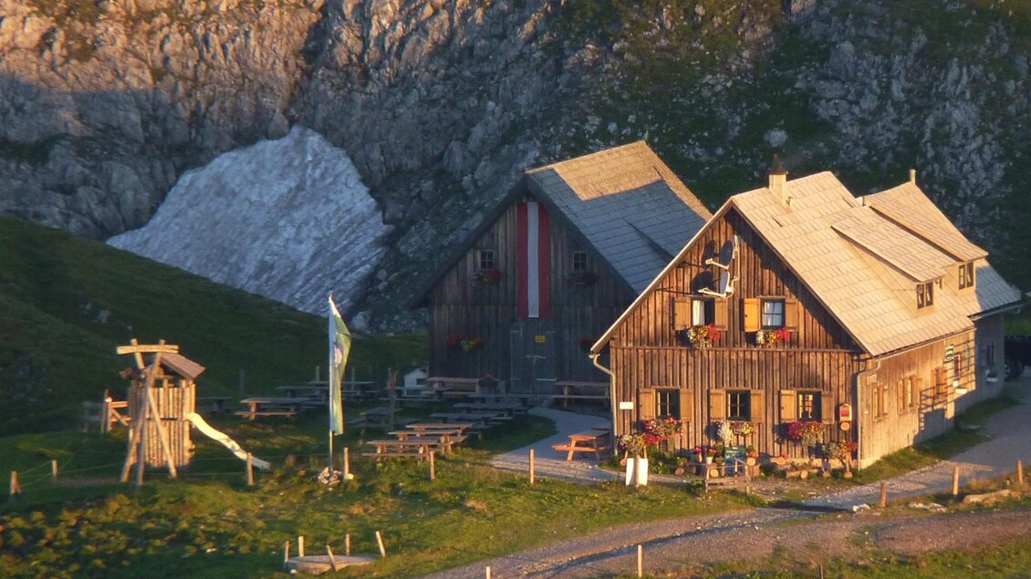 Eine alpine Hütte aus Holz umgeben von grünen Wiesen und Bergen. Im Hintergrund ist ein Gletscher zu sehen. | © Naturpark Mürzer Oberland