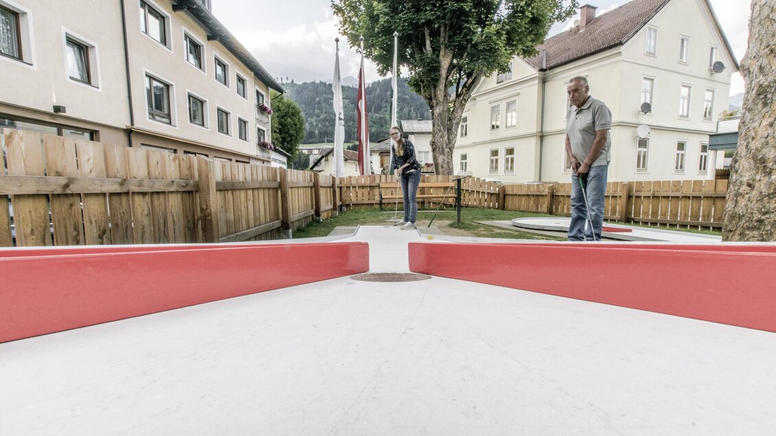 Ein Minigolfplatz im Freien mit roten Hindernissen. Zwei Personen spielen und genießen eine entspannte Atmosphäre. | © Gerhard Pilz