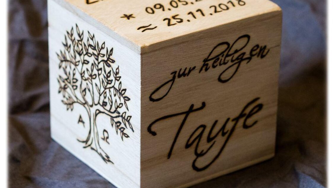 Ein dekorativer Holzwürfel mit gravierten Informationen zur Taufe. Der Würfel zeigt einen Baum und die Daten von Linus Ties. | © Minimi