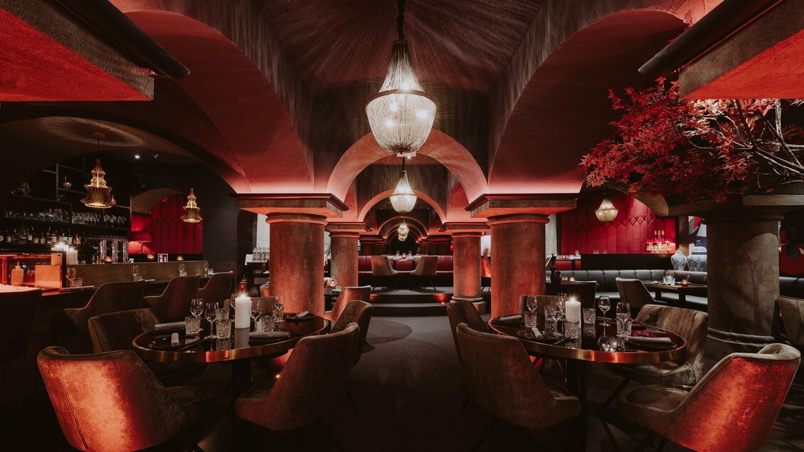 Ein stilvolles Restaurant mit einer eleganten Atmosphäre. Die rot beleuchteten Wände und die geschmackvolle Einrichtung schaffen einladende Sitzbereiche. | © Miss Cho - aiola