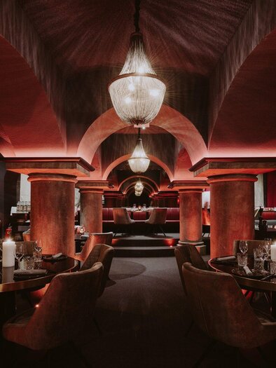 Ein stilvolles Restaurant mit einer eleganten Atmosphäre. Die rot beleuchteten Wände und die geschmackvolle Einrichtung schaffen einladende Sitzbereiche. | © Miss Cho - aiola