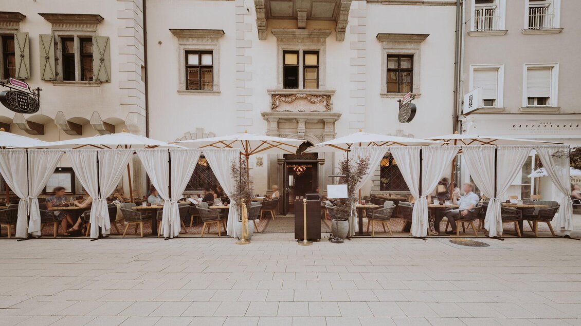 Ein gemütliches Restaurant mit Außenbereich und weißen Sonnenschirmen. Die Tische sind besetzt und es herrscht eine einladende Atmosphäre. | © Miss Cho - aiola
