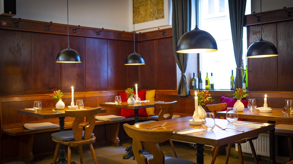 Holztische mit Kerzenlicht, Blumenvasen und Gedecken in einem traditionell eingerichteten Restaurant. | © Graz Tourismus - Werner Krug