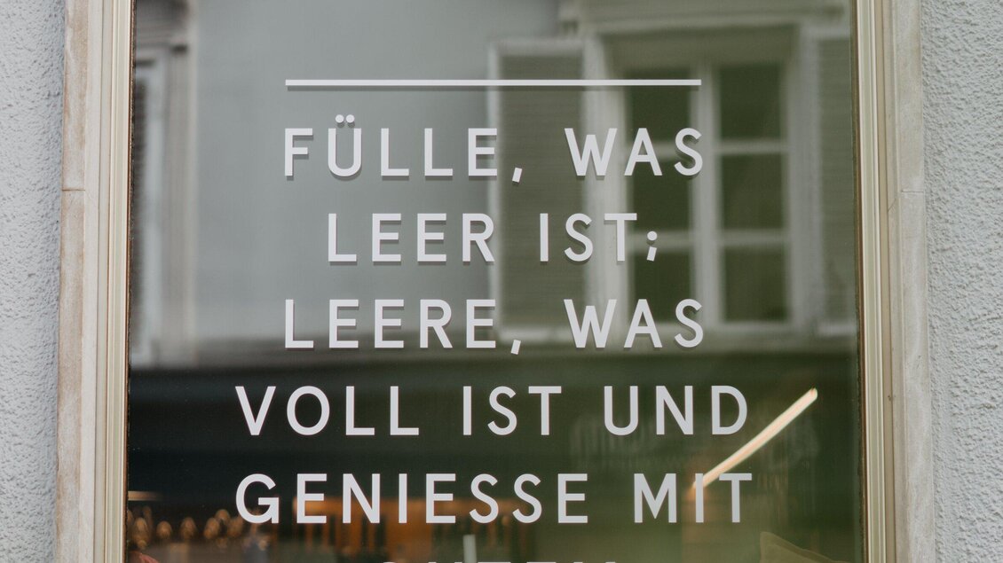 Ein Fenster mit einem Spruch in klarer Schrift. Der Text thematisiert Fülle und Leere im Leben. | © Mohrenwirt