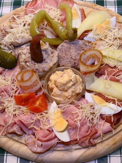 Eine große Platte mit verschiedenen Wurst- und Käsesorten. Dazu sind Gurken, Tomaten und eine Dip-Sauce arrangiert. | © Mur Heuriger