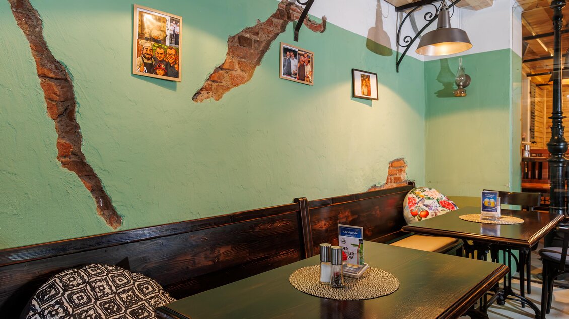 Sitzbereich mit Holztischen, Wanddeko und Polstern im Gastraum des MurWirt in Gössendorf. | © Region Graz-Harry Schiffer