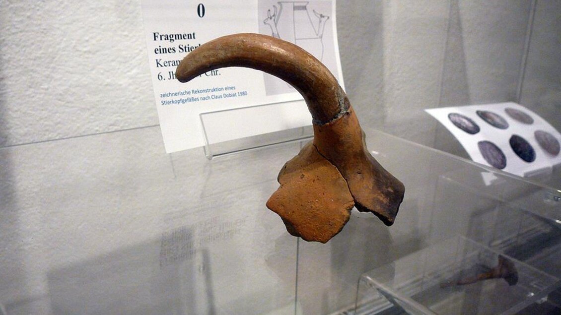 Ein keramisches Fragment in Form eines Horns, präsentiert in einer Vitrine. Es stammt aus dem 6. Jahrhundert v. Chr. und ist Teil einer Ausstellung. | © Ingo Wundrak