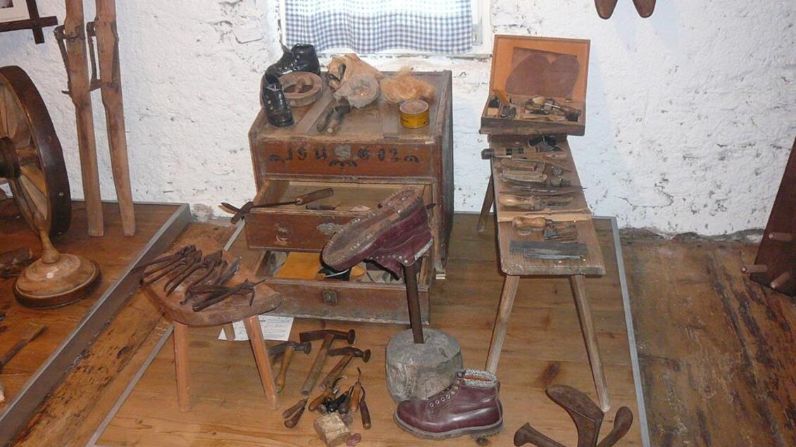In einem alten Werkstatt-Setting sind verschiedene Handwerkszeuge ausgestellt. Unter anderem sind Schuhmacherwerkzeuge und eine Werkbank sichtbar. | © Ingo Wundrak