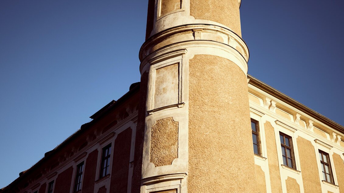 Ein historisches Gebäude mit einem runden Turm. Der Turm hat eine Fahne und ist von blauer Himmel umgeben. | © Armin Walcher