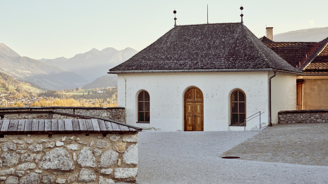 Ein schlichtes, modernes Gebäude mit einem Holz-Dach und großen Fenstern. Im Hintergrund sind sanfte Berge und eine ruhige Landschaft zu sehen. | © Armin Walcher