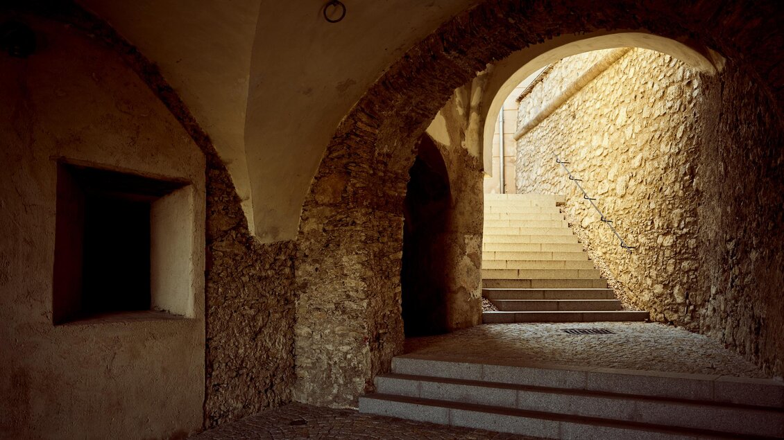 Ein historischer Durchgang mit gewölbten Decken und einem Treppenaufgang. Das Licht fällt sanft auf die steinernen Wände und schafft eine ruhige Atmosphäre. | © Armin Walcher
