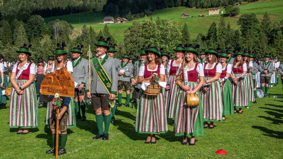 Eine Gruppe von Menschen in traditioneller Tracht steht auf einer Wiese in den Bergen. Die Männer tragen Hüte und die Frauen haben farbenfrohe Kleider und Accessoires. | © MV Kleinsölk
