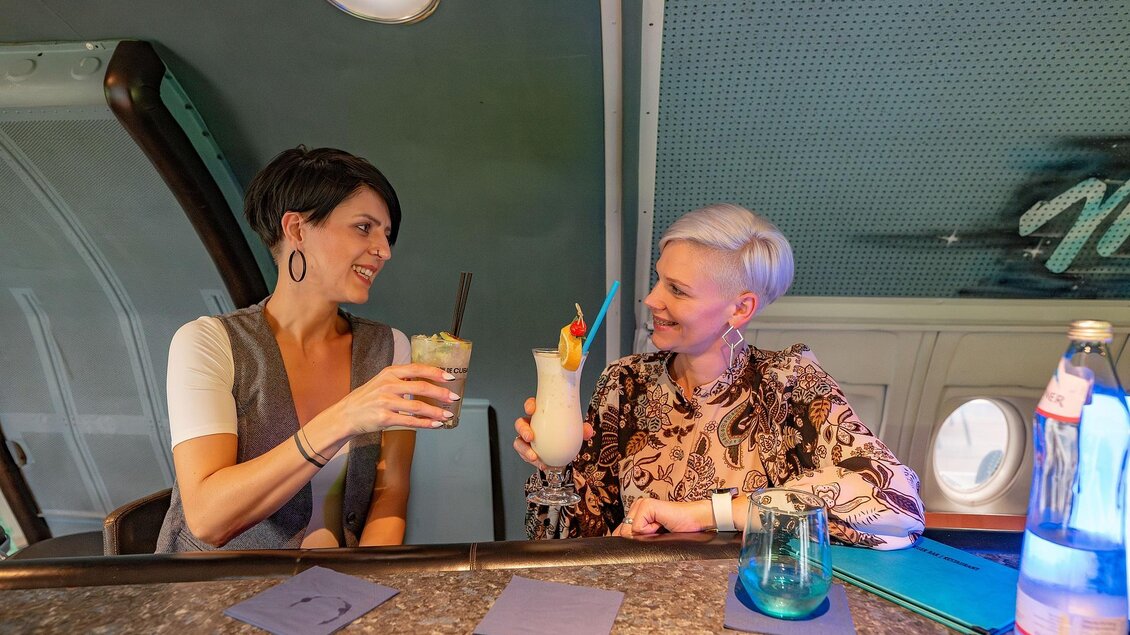 Zwei Frauen sitzen an der Bar und trinken unterschiedliche Cocktails. Eine trinkt einen Mojito und die andere einen Pina Colada.  | © 5komma5sinne - Rene Strasser Fotografie