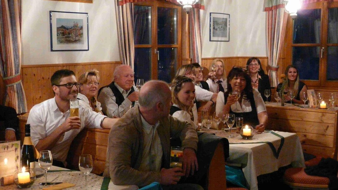 Eine gemütliche Restaurantatmosphäre mit Menschen, die an Tischen sitzen und miteinander sprechen. Die Beleuchtung ist warm und einladend.