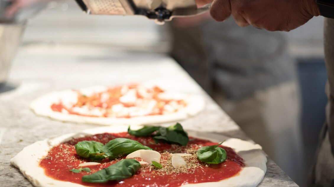 Hand belegt Pizza mit Tomatensauce, Basilikum und Käse | © Napo Graz - fiedlerphoto