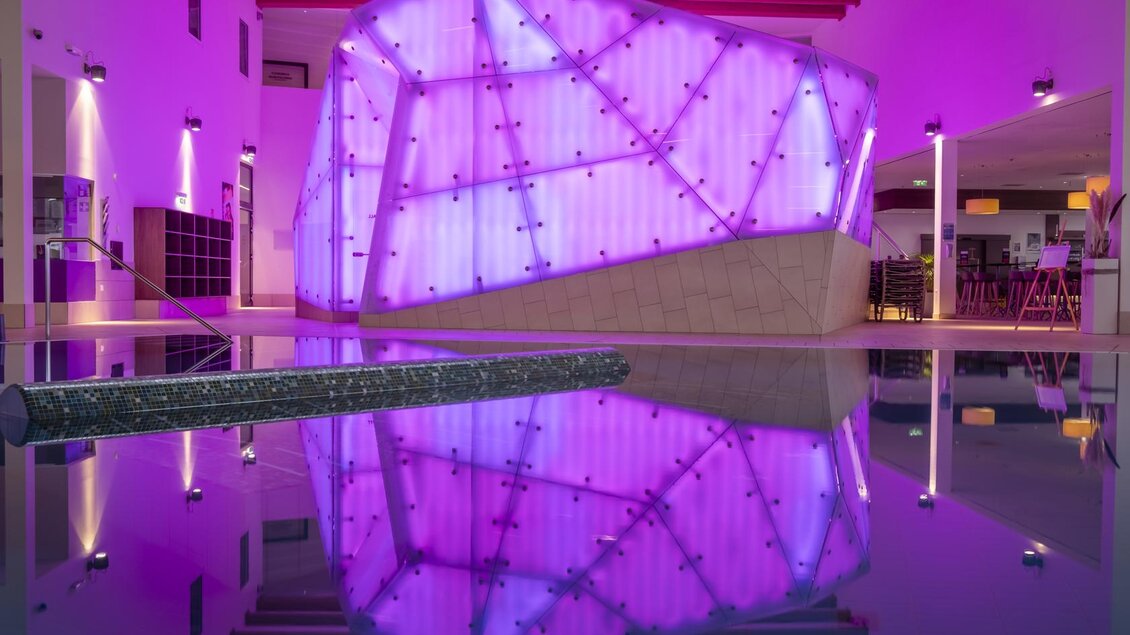 Ein moderner Innenraum mit einer auffälligen, pinken Lichtinstallation. Der Boden reflektiert das Licht und sorgt für eine stimmungsvolle Atmosphäre. | © Thomas Lahnsteiner