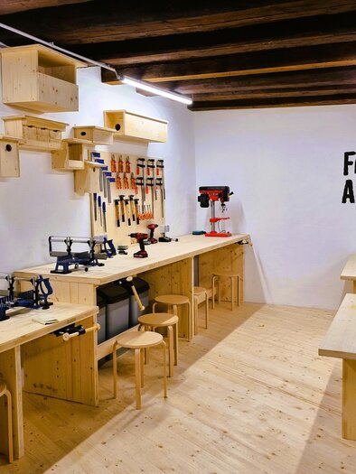 Ein helles Forscher-Atelier mit Holzarbeiten und Werkzeugen. Die Wände sind mit Regalen und verschiedenen Werkzeugen ausgestattet.