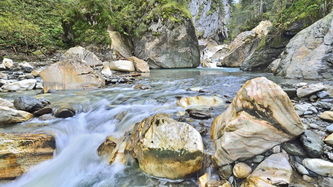 Ein schöner Fluss fließt zwischen großen Steinen und grünen Bäumen. Die Natur ist friedlich und einladend. | ©  Herfried Marek