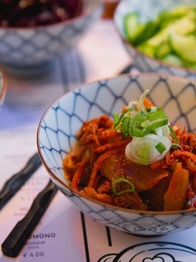 A selection of small bowls with colorful vegetables. In the foreground is a bowl with carrot-like vegetables and spring onions. | © Noonbar - Moriwano Group