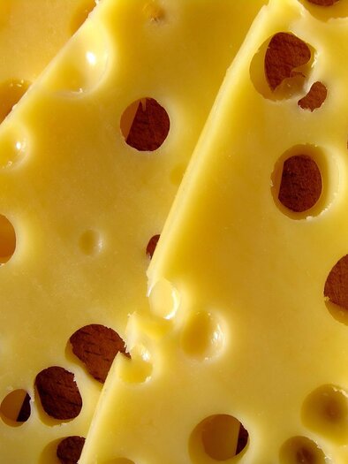 A piece of cheese with many holes. The cheese slices are yellow and thinly sliced. | © Pixabay