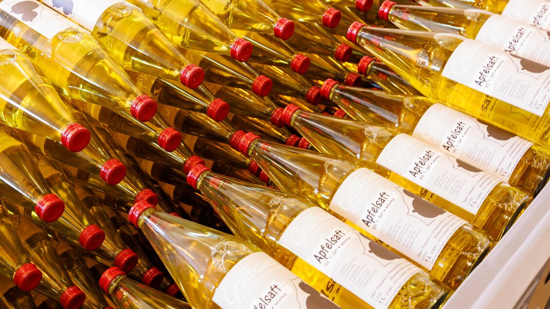 Eine große Menge von Flaschen mit gelbem Flüssigkeit, aufgereiht in Regalen. Jede Flasche hat ein weißes Etikett mit einem roten Deckel. | © TV Region Graz-Harry Schiffer