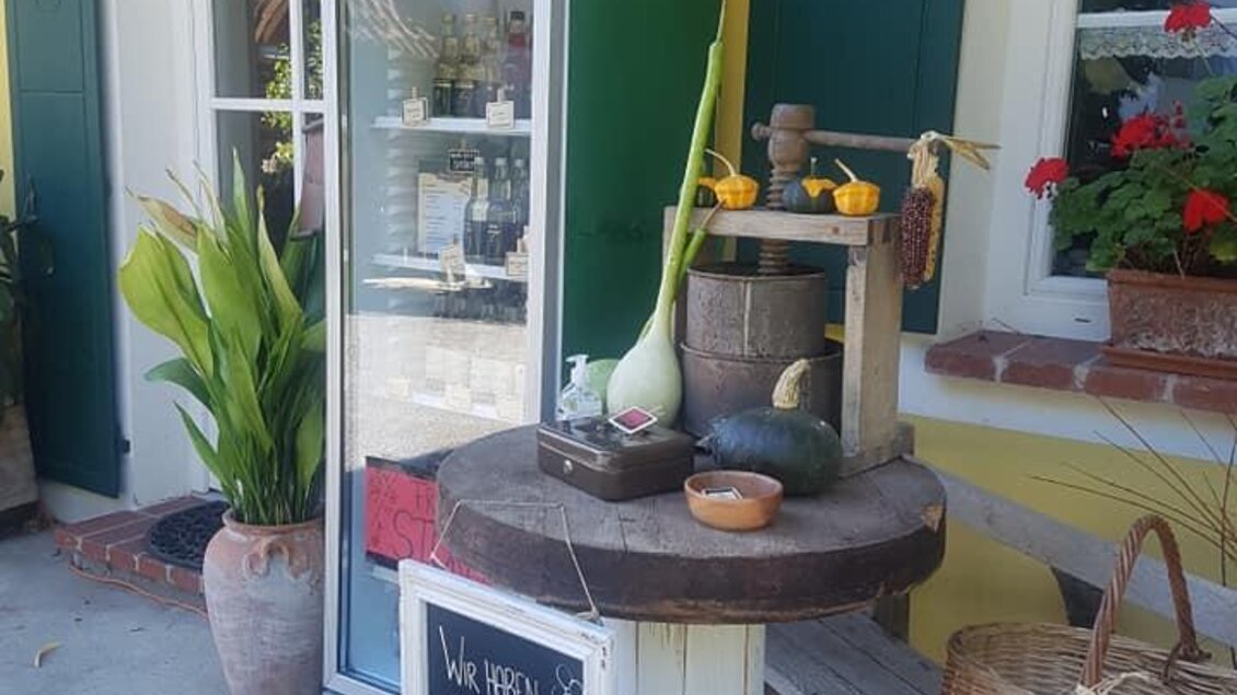 Ein einladender Verkaufsstand mit frischem Gemüse und Kräutern. Neben der Kühltruhe steht ein Holzregal mit weiteren Produkten. | © Obsthof Braunstein