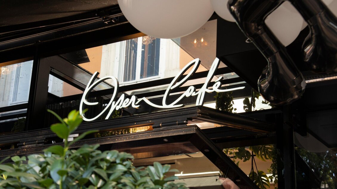 Ein Café mit dem Schriftzug "Opera Café" ist zu sehen. Die Umgebung ist modern und einladend mit Pflanzen und Tageslicht. | © Operncafé - Jauk Katharina