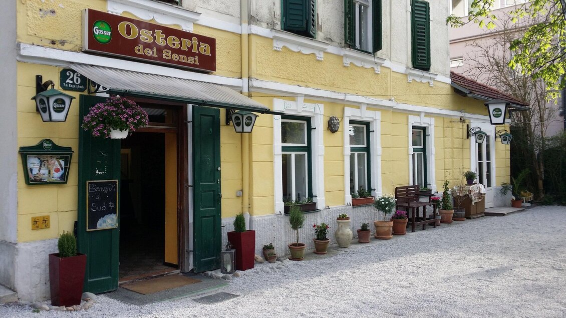 Ein einladendes Restaurant mit dem Namen "Osteria dei Sensi". Die Fassade ist gelb mit vielen Pflanzen und Blumen in Töpfen. | © Osteria dei Sensi