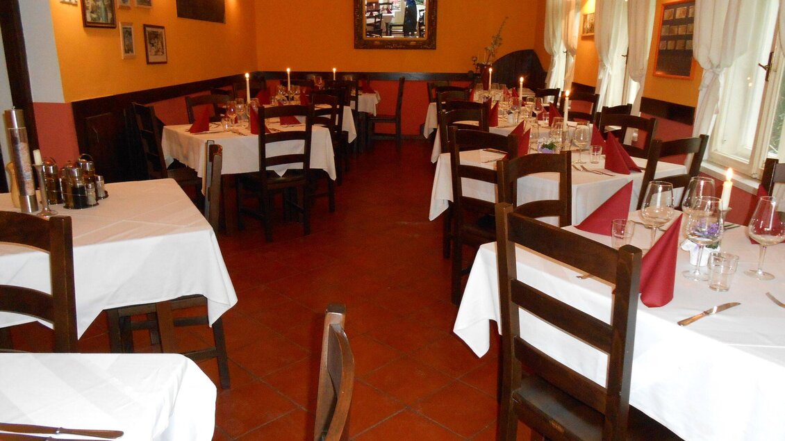 Ein gemütliches Restaurant mit weißen Tischdecken und Laternen. Die Tische sind ordentlich eingedeckt und bieten einladende Atmosphäre. | © Osteria dei Sensi