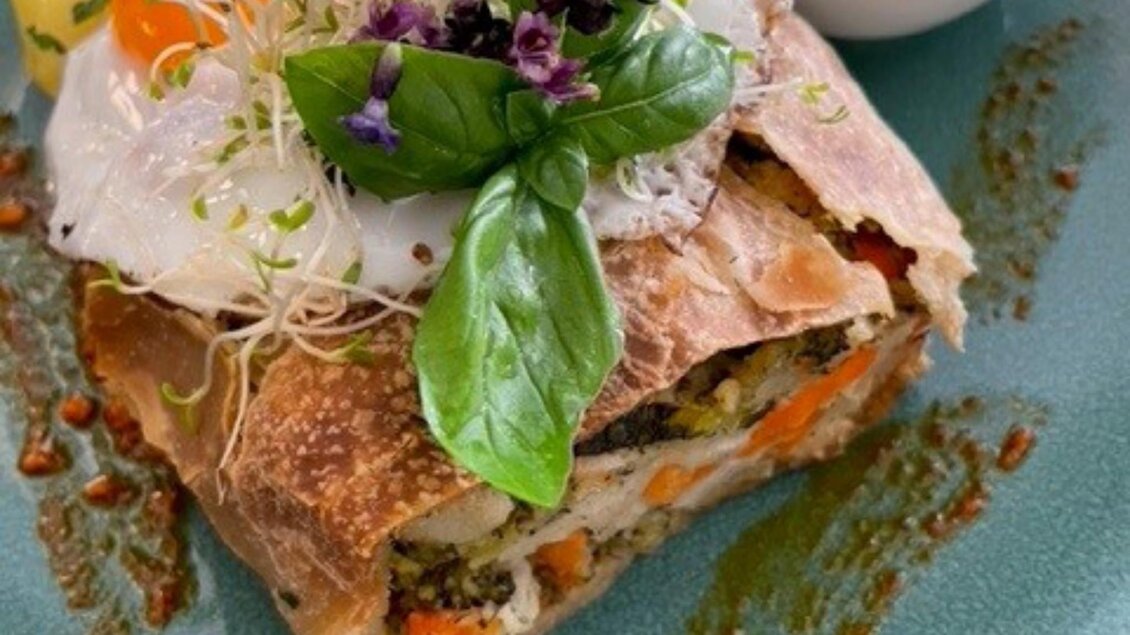 Gemüse-Kräuterstrudel mit pochiertem Ei, Sprossen, Basilikum und Dip auf grünem Teller. | © PEP