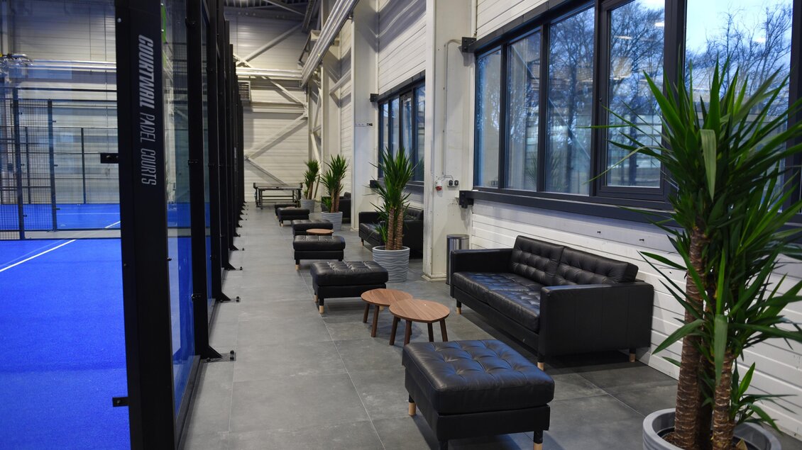 Schwarze Ledersofas und Pflanzen in der Lounge neben dem Padelplatz in Kainbach bei Graz. | © Alexander Veit