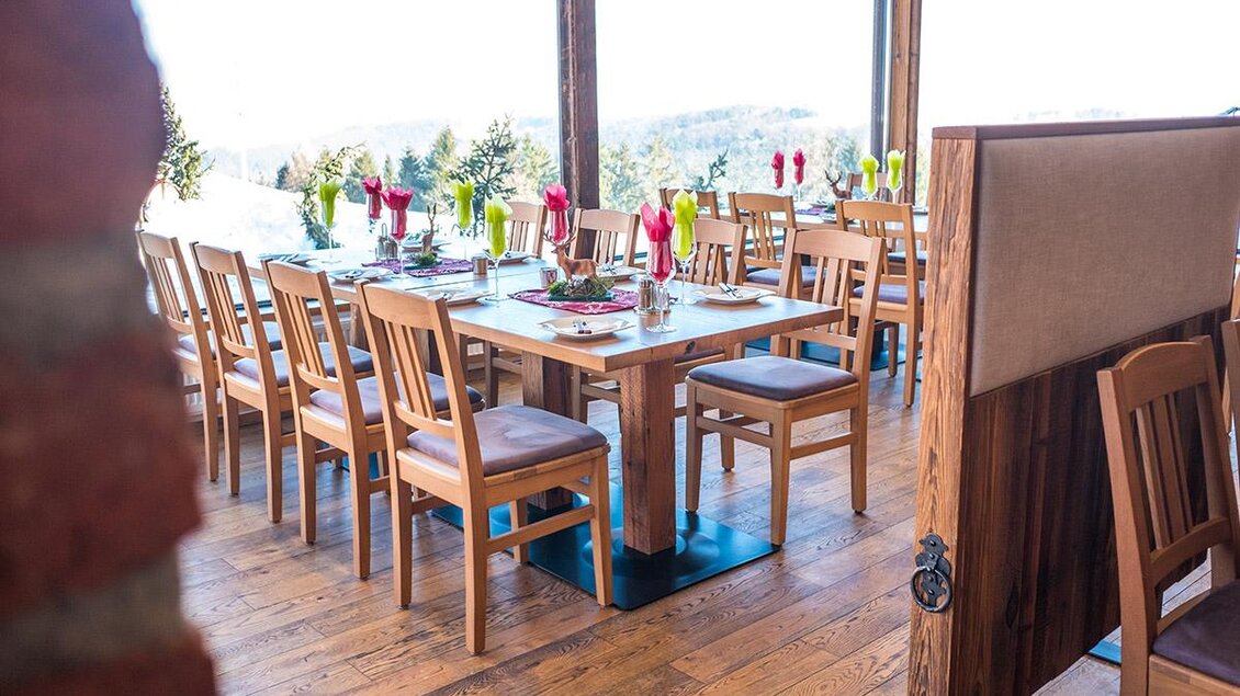 Ein einladendes Restaurant mit Holzstuhl und schön gedeckten Tischen. Große Fenster bieten einen Blick auf die umliegende Landschaft. | © Wein- und Genusswelt Garber