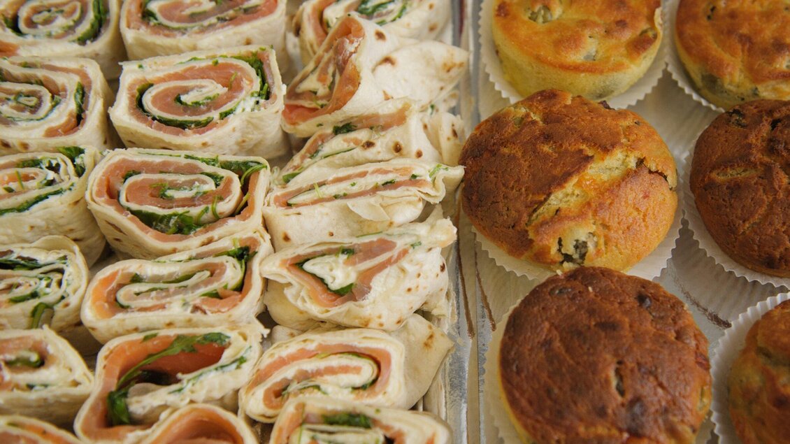 Eine Platte mit Wraps, gefüllt mit Lachs und Gemüse, und frisch gebackenen Muffins. Die appetitlichen Snacks sind ideal für ein Buffet. | © Parks - Martin Pabis & Martina Rötzer
