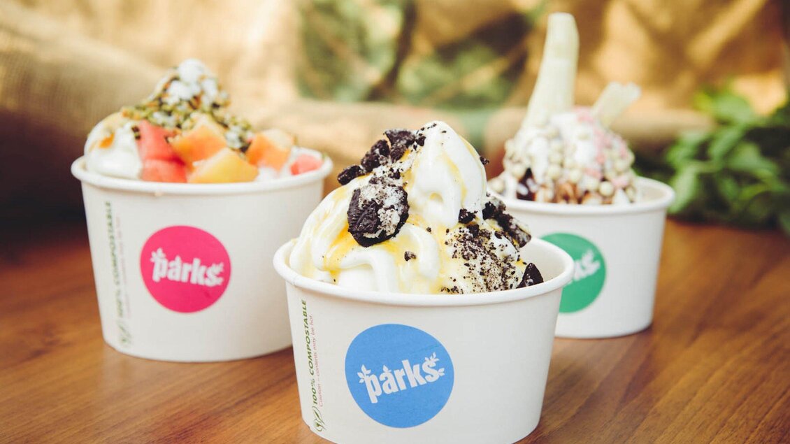 Drei Becher mit verschiedenen Eissorten sind auf einem Tisch angeordnet. Die Eissorten sind mit Toppings wie Obst, Schokolade und Nüssen dekoriert. | © Parks - Martin Pabis & Martina Rötzer