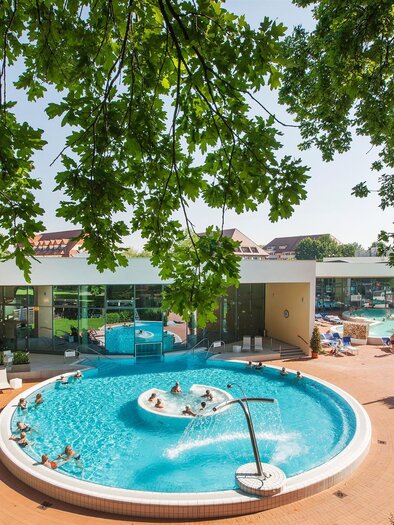 An inviting pool area with a round basin and lounge chairs. Surrounded by green grass and trees, the facility offers a relaxed atmosphere. | © Harald Eisenberger