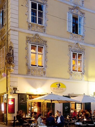 An inviting street café in a busy alley. The colorful tables under the umbrellas invite you to linger. | © CMS