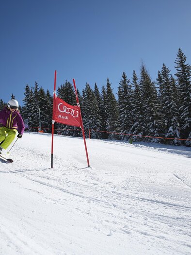 Ein Skifahrer fährt eine Piste hinunter, umgeben von schneebedeckten Bäumen. Der Himmel ist klar und blau. | © Gregor Hartl
