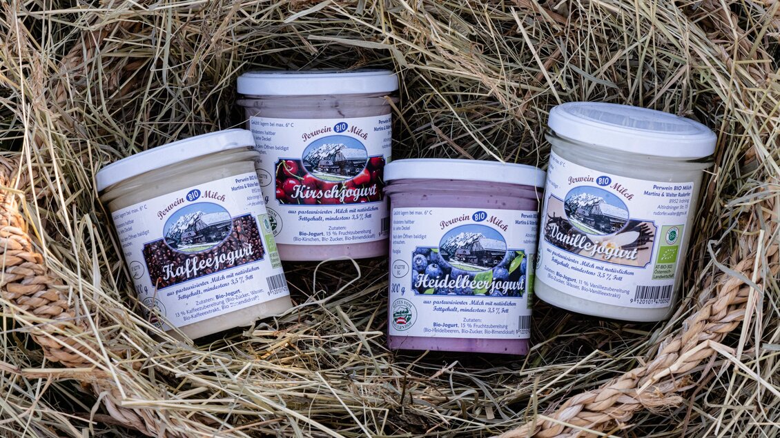 Vier Becher mit verschiedenen Geschmacksrichtungen sind in einem Nest aus Heu angeordnet. Die Produkte sind in einer rustikalen Verpackung, die auf natürliche Zutaten hinweist. | © Martina Siebenhandl