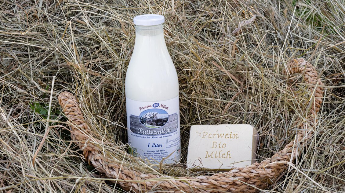 Eine Flasche Milch steht in einem Korb auf trockenem Heu. Neben der Milch liegt ein Stück Käse mit der Aufschrift "Fermeda Bio Milch". | © Martina Siebenhandl