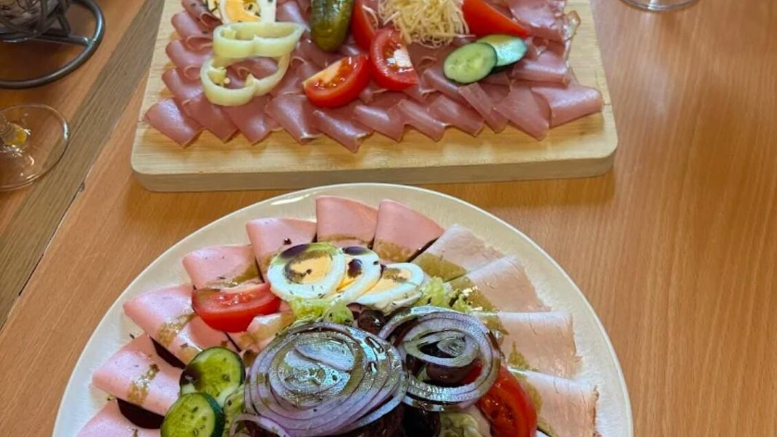 Eine attraktive Präsentation von Wurst- und Käsesorten, garniert mit Gemüse und Eiern. Im Hintergrund ist ein weiterer Teller mit ähnlichem Aufschnitt zu sehen. | © Janisch