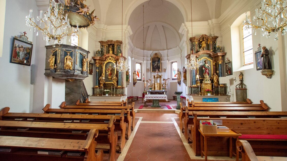 Ein Blick in eine Kirche mit Holzbanken und kunstvollen Altären. Der Raum ist hellbeleuchtet und strahlt eine ruhige Atmosphäre aus. | © Kurkommission Bad Blumau