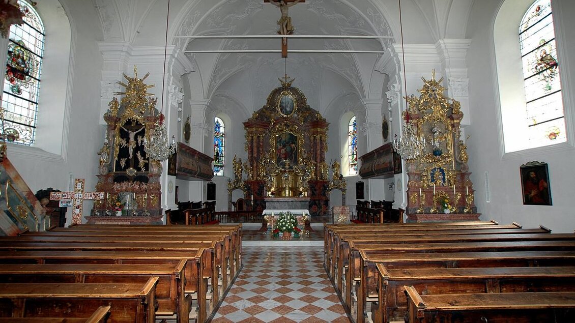 Eine wunderschöne Kirche mit einer beeindruckenden Innenausstattung. Die Holzbänke sind auf den Altar ausgerichtet, und bunte Glasfenster bringen Licht ins Innere. | © TVB Haus-Aich-Gössenberg